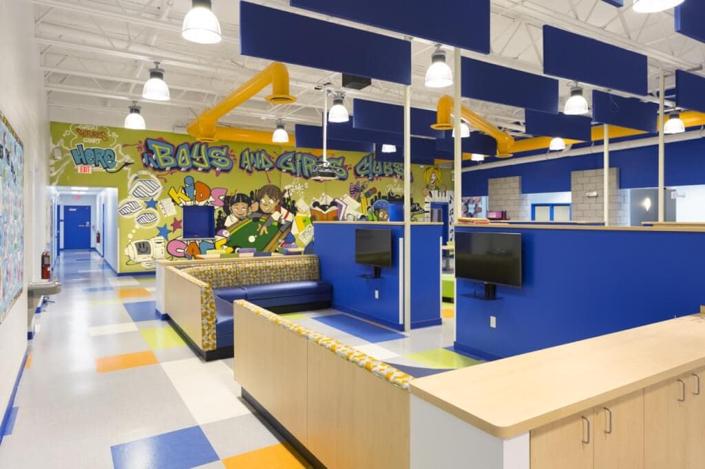 Gaming area with sectional furniture graffiti mural bright colors exposed structure exposed ductwork Rochester NY